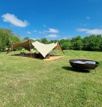 7.5m x 10.5m Chino Stretch Floating Tent with Corners Down, pitched next to a fire pit
